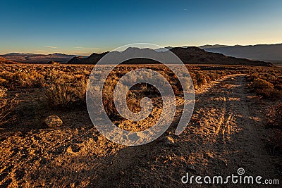 Dirt road in high desert landscape to distant dark hills and snowy mountains Stock Photo