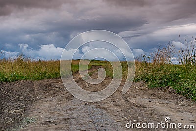 Dirt road leading to the top of the hill, dramatic storm clouds at summertime Stock Photo