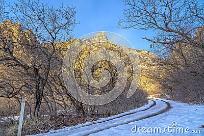 Dirt road in snowy Provo Canyon against mountain and blue sky in winter Stock Photo