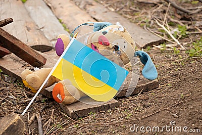 A dirty broken children`s toy and the flag of Ukraine lies in the yard during the war in Ukraine, the death of children at the Stock Photo