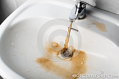 Dirty brown water running into a sink Stock Photo