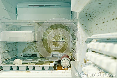 Dirty freezer of modern refrigerator with splash of carbonated drink, open white refrigerator inside fridge with shelves and ice m Stock Photo