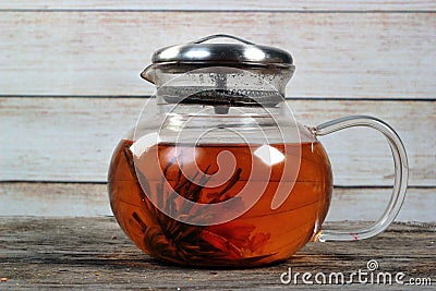 Dirty glass teapot with tea flower on old wooden table Stock Photo