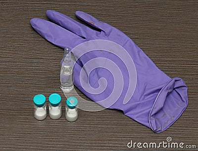 Dirty glove with vaccine vials on table Stock Photo