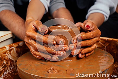 Dirty hands close up . romantic couple in love working together on potter wheel and sculpting clay pot,a bearded man and Stock Photo