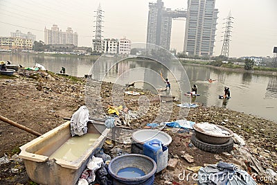 Dirty Laundry: Washerman wash clothes in polluted water Editorial Stock Photo