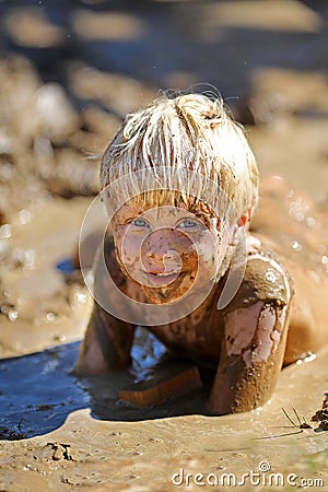 Dirty Little Child Laying in A Wet Mud Puddle Stock Photo