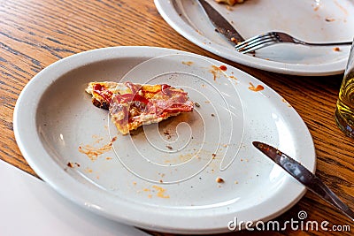 Dirty messy plates after pizza eating with unclean used utensils in the cafe. Stock Photo