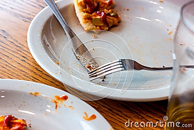 Dirty messy plates after pizza eating with unclean used utensils in the cafe. Stock Photo