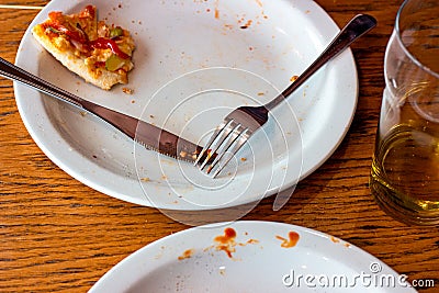 Dirty messy plates after pizza eating with unclean used utensils in the cafe. Stock Photo