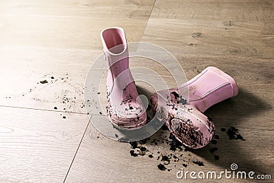 Dirty muddy kids rubber rain boots on laminate floor Stock Photo