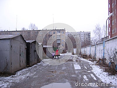 Dirty raw street go people pass between garages Novosibirsk Stock Photo