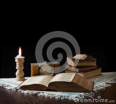 Old bible on the background of a clock and a candle Stock Photo