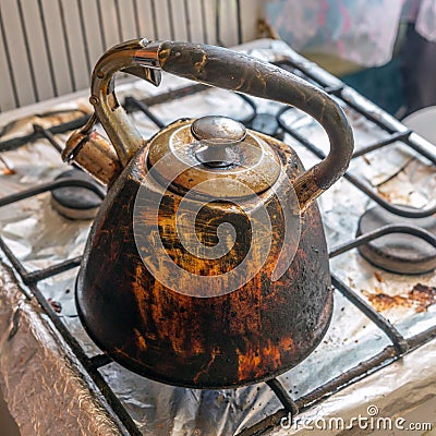 Dirty smoked kettle stands on a gas stove Stock Photo