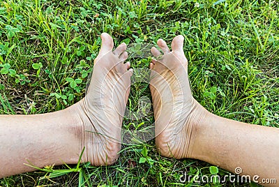 Dirty soles of the adult feet on the green grass Stock Photo