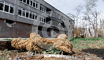 dirty toys on the background of a burned-out destroyed school in an abandoned city in Ukraine Stock Photo