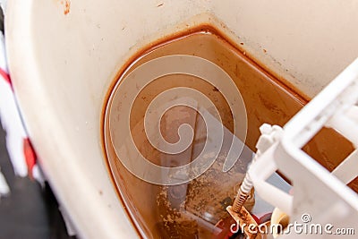 Dirty unhygienic rusty and calcified flush tank of toilet with limescale and rust stains and scum close up need to be cleaned and Stock Photo