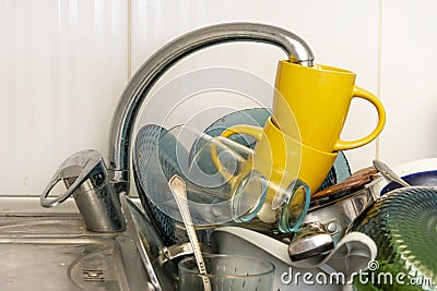 Dirty and unwashed dishes are stacked in the kitchen sink. A mountain of not clean and used tableware. Stock Photo