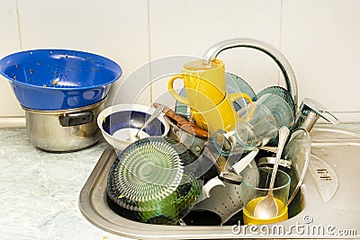 Dirty and unwashed dishes are stacked in the kitchen sink. A mountain of not clean and used tableware. Stock Photo