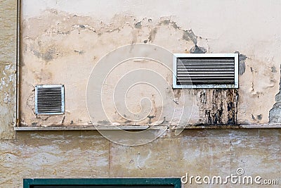 Dirty ventilation grill with drips of industrial grease on the weathered peeling back wall of the cafe Stock Photo