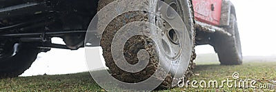 Dirty wheel with rubber tire of car parked on green grass Stock Photo
