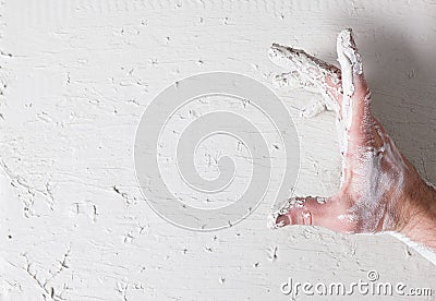 Dirty worker hand in stucco on white plaster wall Stock Photo