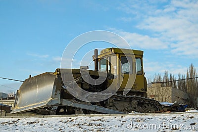 Dirty yellow bulldozer. on the winter road because construction stopped Stock Photo