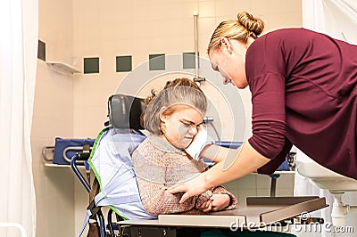 Disability a disabled child in a wheelchair being cared for by a nurse Stock Photo