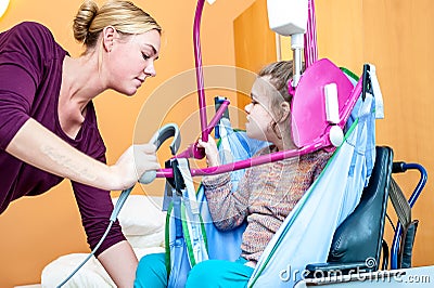 A disabled girl being lifted into a wheelchair Stock Photo