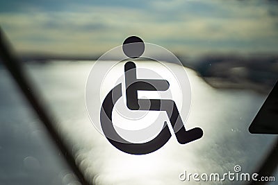 Disable wheelchair sign in public transportation on door glass with the background of sun reflection in the ocean sunset time in Stock Photo