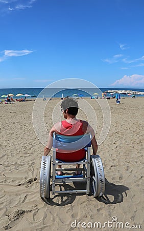 Disabled adult looks at the sea from a wheelchair Stock Photo