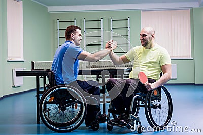 Disabled adult men shaking hands after playing table tennis Stock Photo