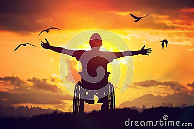 Disabled handicapped man has a hope. He is sitting on wheelchair and stretching hands at sunset Stock Photo