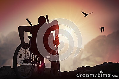 Disabled handicapped man has a hope. He is sitting on wheelchair and stretching hands at sunset Stock Photo