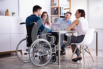 Disabled Manager Sitting With His Colleagues Stock Photo