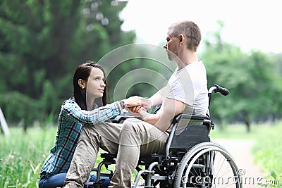 Disabled male veteran is sitting in wheelchair woman is sitting nearby Stock Photo