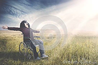 Disabled man sits on wheelchair at field Stock Photo