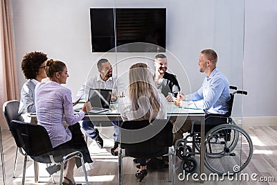 Disabled Manager Sitting With His Colleagues Stock Photo