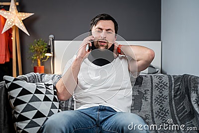 Disabled painful man with neck brace talking on phone at home. Man with spine trauma in neck brace cervical call Stock Photo