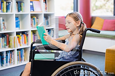 Disabled school girl reading book in library Stock Photo