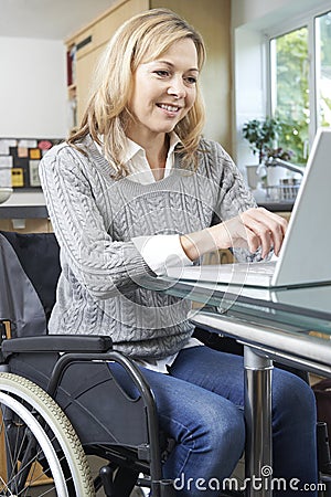Disabled Woman In Wheelchair Using Laptop At Home Stock Photo