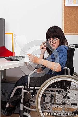 Disabled young girl on wheelchair working in her office Stock Photo