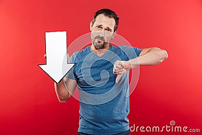Disappointed adult guy 30s holding blank speech arrow pointer di Stock Photo