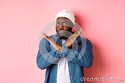 Disappointed Black man, staring at camera displeased and frowning, showing stop cross gesture, prohibit and disagree Stock Photo