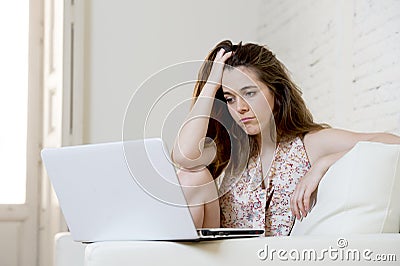 Disappointed girl at home couch using internet for studying with laptop computer Stock Photo