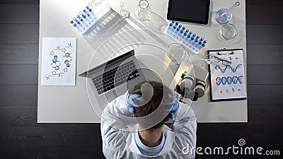 Disappointed laboratory worker sitting upset by experiment failure, top view Stock Photo