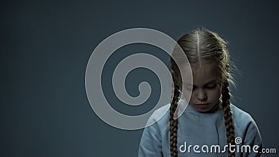 Disappointed little child looking down, orphan girl missing parents, homeless Stock Photo