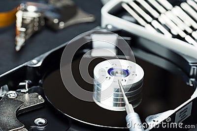 Disassembled hard disk drive inside close-up, spindle, actuator arm, read write head, platter, disassembly tools Stock Photo
