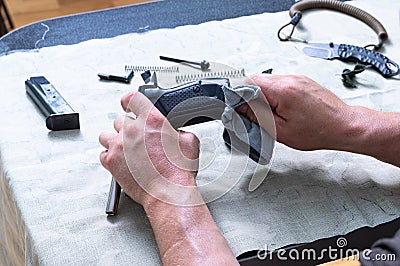 Disassembled pistol, safety cord and knife. Thorough cleaning of the gun. Pistol and cleaning cloth in hand Stock Photo