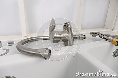 Disassembled water tap and pipe wrench near sink on countertop Stock Photo